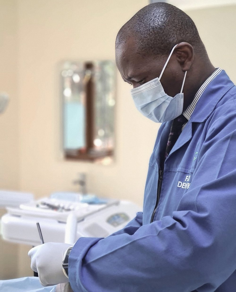 A Family Dentistry Nairobi dentist in the clinic's blue coat, treating a patient