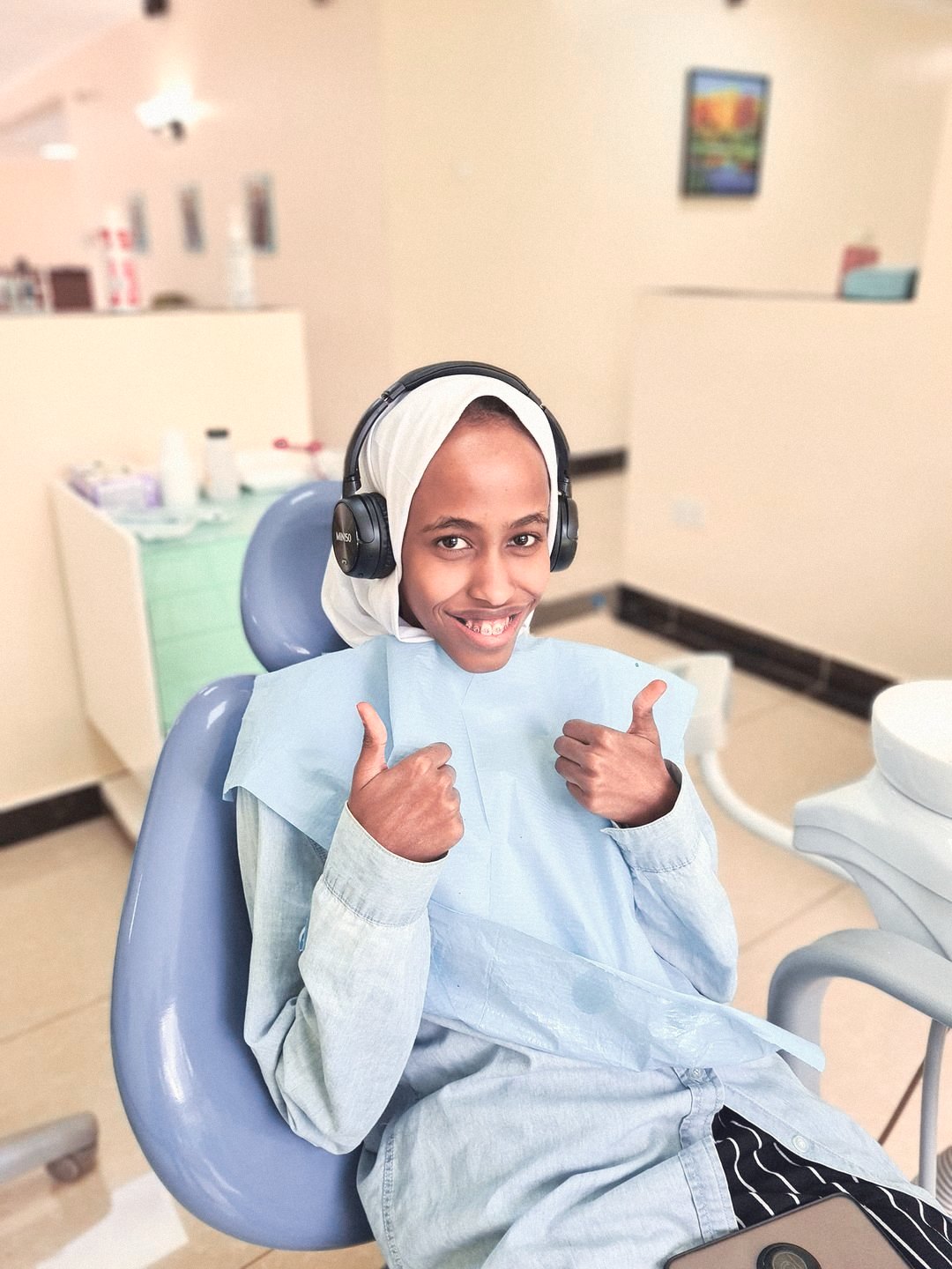 A smiling young patient giving two thumbs up in the dental chair